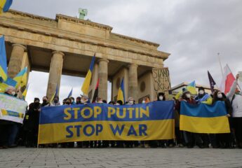 Vor dem Brandenburger Tor halten Demonstrierende eine Flagge in blau-gelb mit der Aufschrift "Stop Putin Stop War"